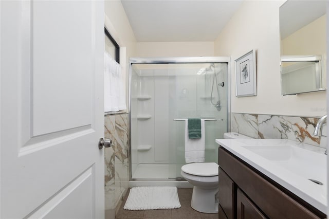 bathroom with wainscoting, a shower stall, tile walls, and vanity