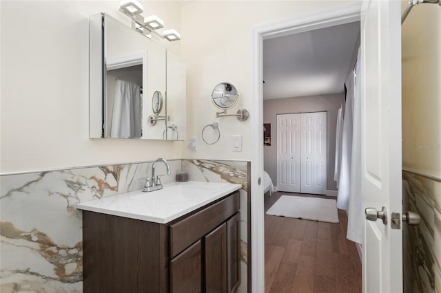 bathroom with vanity, tile walls, wood finished floors, and wainscoting