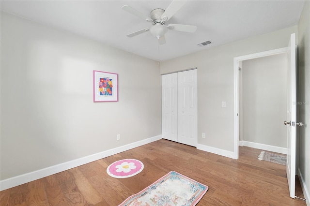 unfurnished bedroom featuring a closet, a ceiling fan, baseboards, and wood finished floors