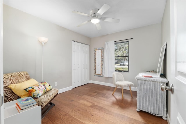 sitting room featuring radiator, a ceiling fan, baseboards, and wood finished floors