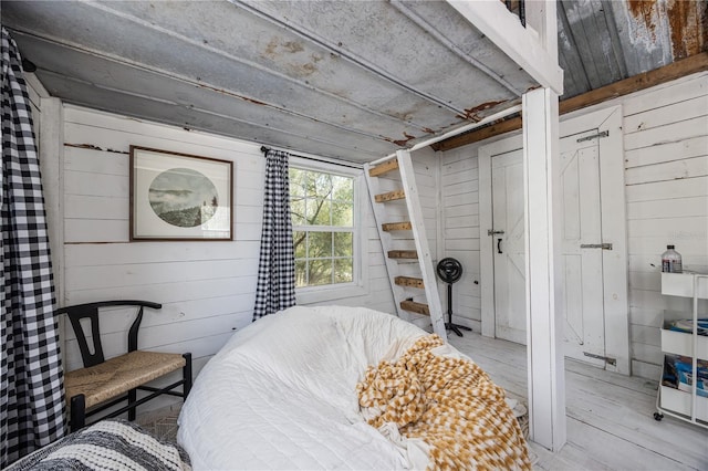 bedroom featuring wood finished floors and wooden walls