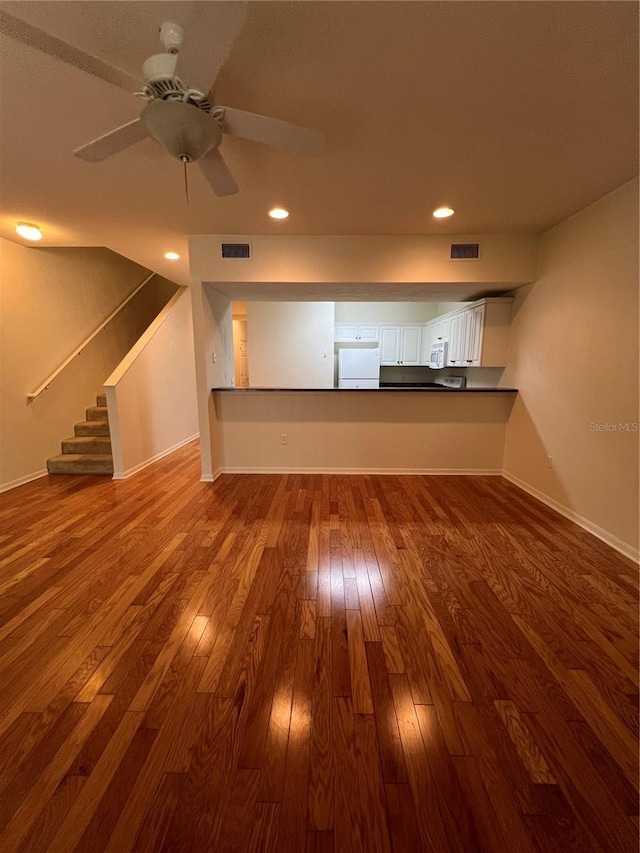 unfurnished living room featuring baseboards, visible vents, dark wood-type flooring, stairs, and recessed lighting