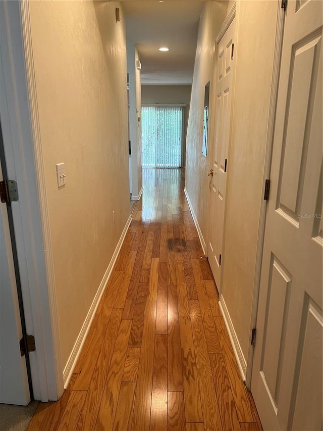 corridor featuring hardwood / wood-style floors and baseboards