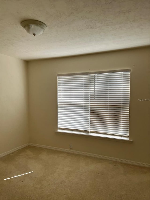 carpeted spare room with a textured ceiling and baseboards