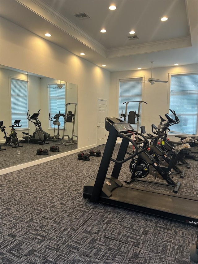 exercise room with ornamental molding, recessed lighting, a raised ceiling, and visible vents