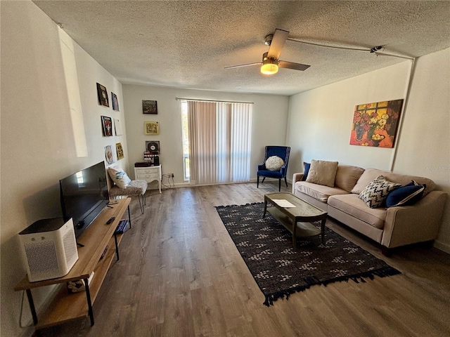 living area with a ceiling fan, a textured ceiling, and wood finished floors