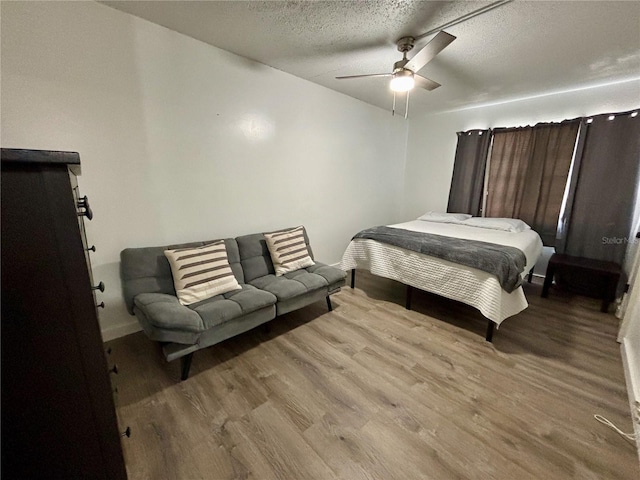 bedroom with a textured ceiling, wood finished floors, and a ceiling fan