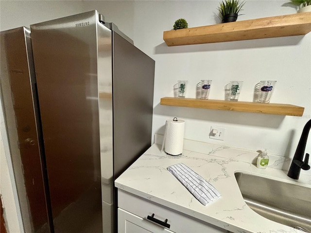 kitchen with white cabinets, light stone countertops, open shelves, and freestanding refrigerator