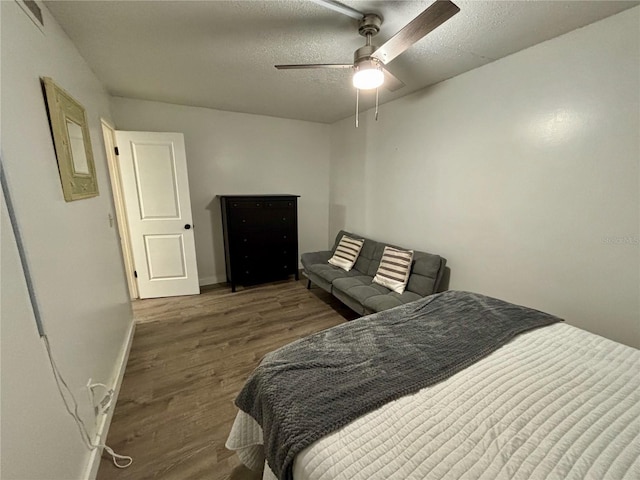 bedroom with ceiling fan, a textured ceiling, baseboards, and wood finished floors