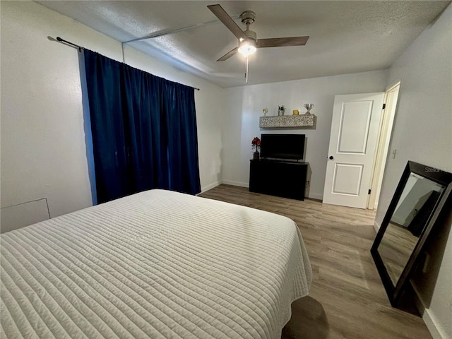 bedroom with a textured ceiling, wood finished floors, a ceiling fan, and baseboards