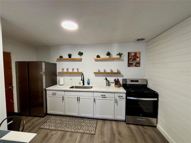 kitchen featuring visible vents, dark wood-type flooring, stainless steel appliances, open shelves, and a sink