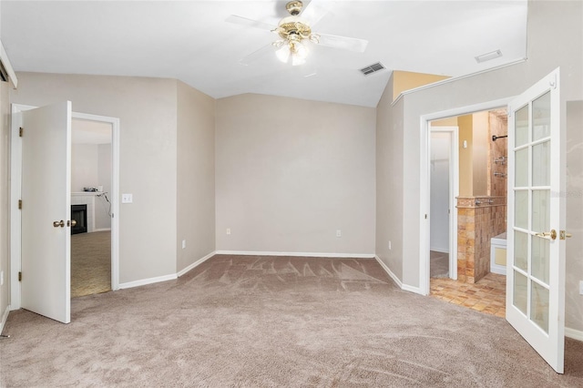 unfurnished bedroom featuring a fireplace, carpet, visible vents, and french doors