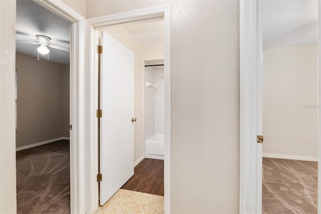 hallway with tile patterned flooring, baseboards, and carpet