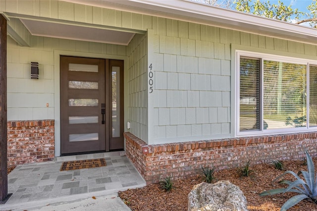 view of exterior entry featuring brick siding