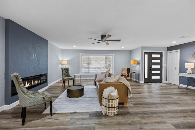 sitting room featuring recessed lighting, a ceiling fan, a large fireplace, wood finished floors, and baseboards