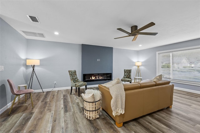 living room featuring a fireplace, wood finished floors, visible vents, and baseboards