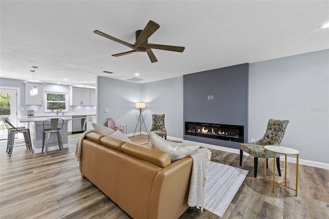 living room with a glass covered fireplace, light wood-style flooring, baseboards, and recessed lighting