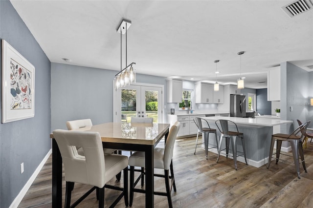 dining space with visible vents, baseboards, wood finished floors, and french doors