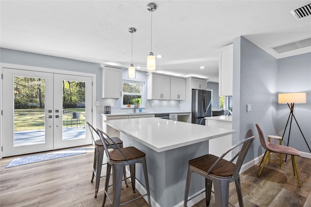 kitchen with visible vents, a kitchen breakfast bar, light countertops, stainless steel appliances, and french doors