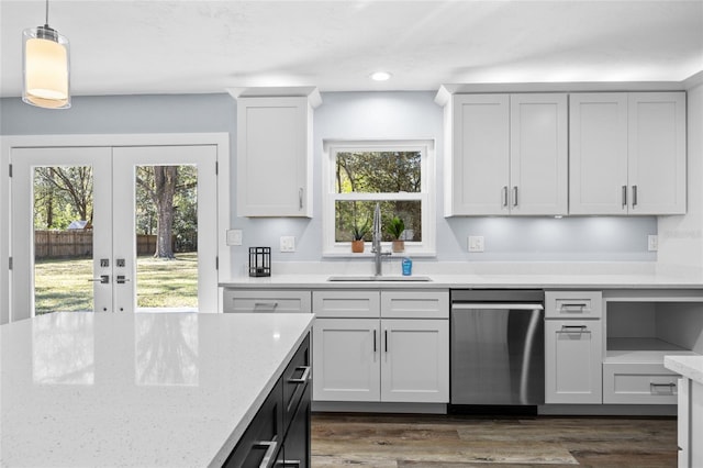 kitchen with a sink, dark wood-type flooring, stainless steel dishwasher, and decorative light fixtures