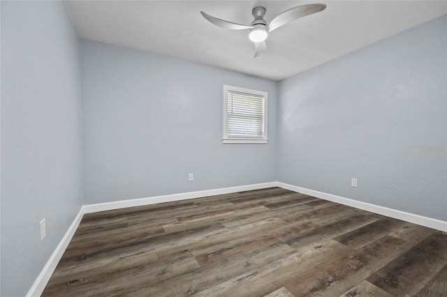 empty room featuring dark wood-style flooring, a ceiling fan, and baseboards