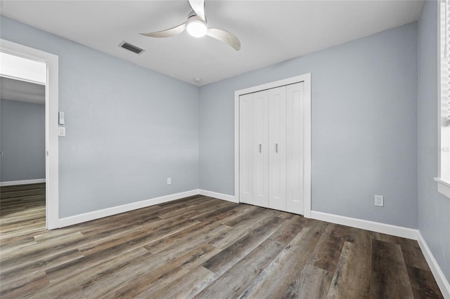 unfurnished bedroom with baseboards, a closet, visible vents, and wood finished floors