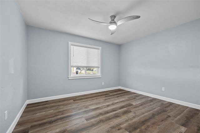 spare room featuring dark wood-type flooring, ceiling fan, and baseboards