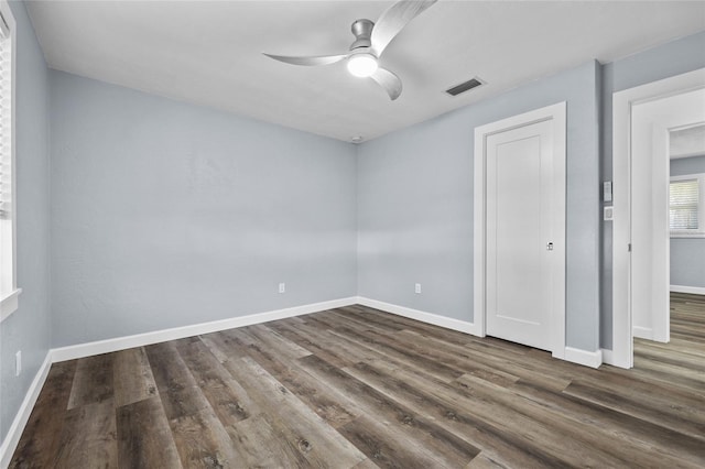 unfurnished bedroom featuring dark wood-style floors, visible vents, ceiling fan, and baseboards