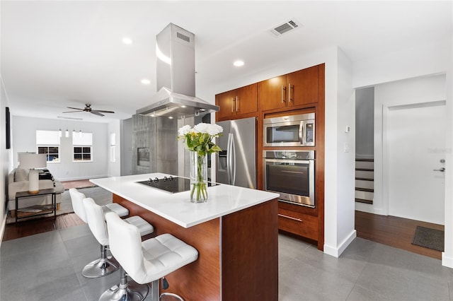 kitchen featuring a breakfast bar area, visible vents, light countertops, appliances with stainless steel finishes, and island exhaust hood