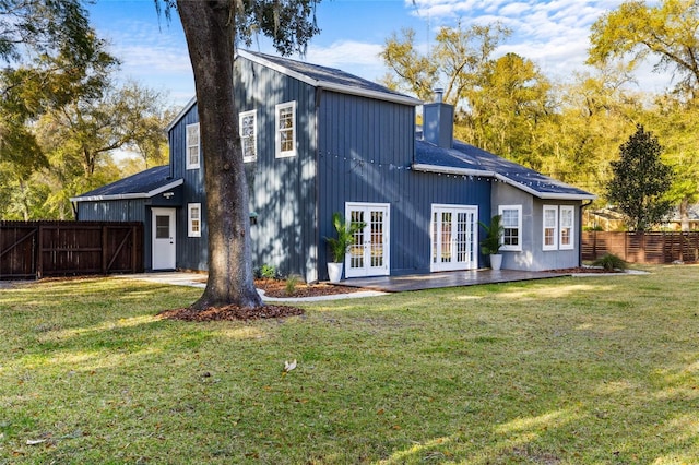 rear view of property featuring a yard, french doors, a chimney, and fence