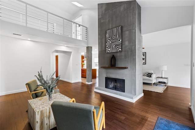 living area with a large fireplace, visible vents, baseboards, and wood finished floors