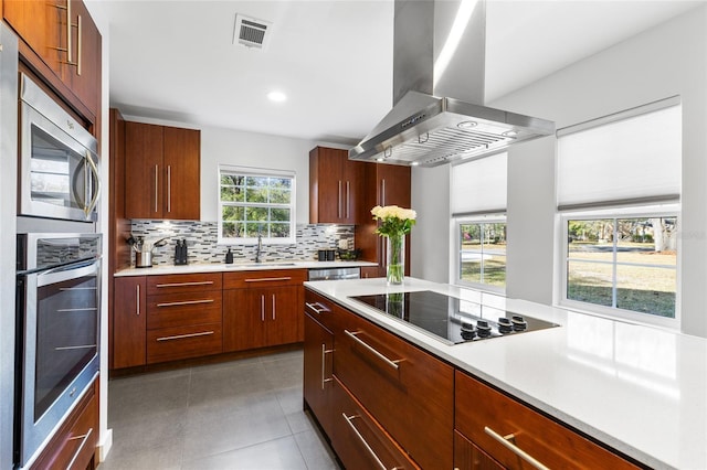 kitchen featuring island exhaust hood, black electric stovetop, light countertops, visible vents, and modern cabinets