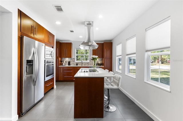 kitchen featuring visible vents, a kitchen breakfast bar, stainless steel appliances, light countertops, and backsplash