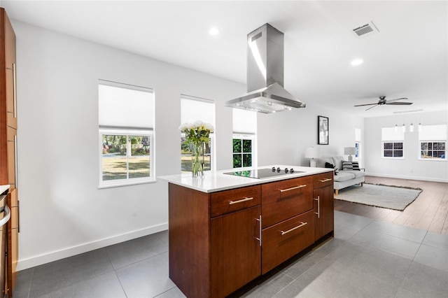 kitchen featuring visible vents, island range hood, a center island, black electric cooktop, and light countertops