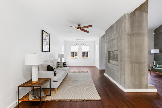 living area with ceiling fan, a fireplace, baseboards, and dark wood-type flooring