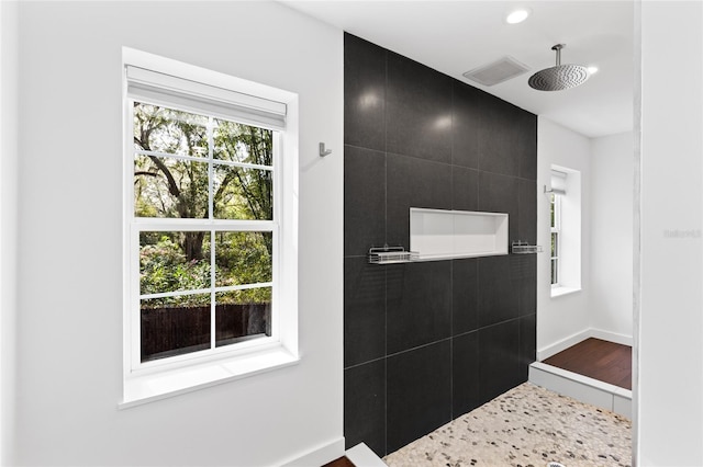 bathroom with baseboards, visible vents, a tile shower, and recessed lighting