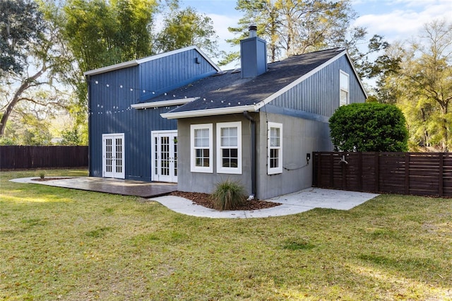 back of property with a patio area, french doors, a fenced backyard, and a yard