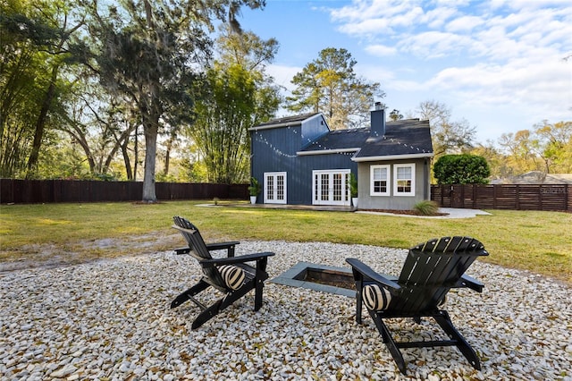 back of property with an outdoor fire pit, a lawn, a fenced backyard, and french doors