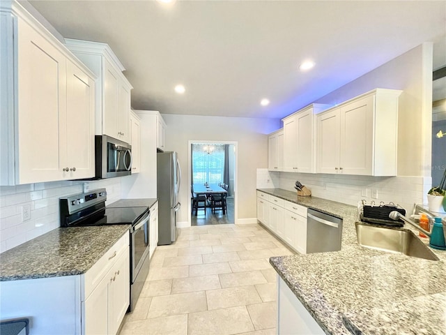 kitchen featuring stainless steel appliances, a sink, dark stone countertops, and tasteful backsplash