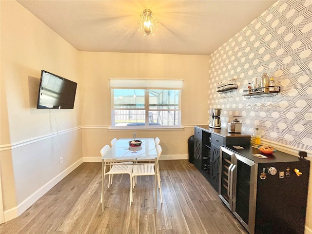 dining area featuring wallpapered walls, an accent wall, baseboards, and wood finished floors