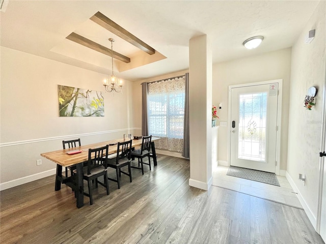 dining room with baseboards, a chandelier, a raised ceiling, and wood finished floors