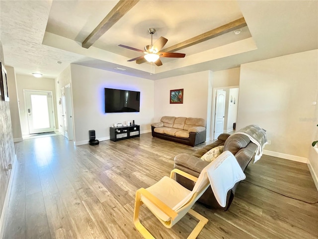 living room with baseboards, a raised ceiling, and hardwood / wood-style floors