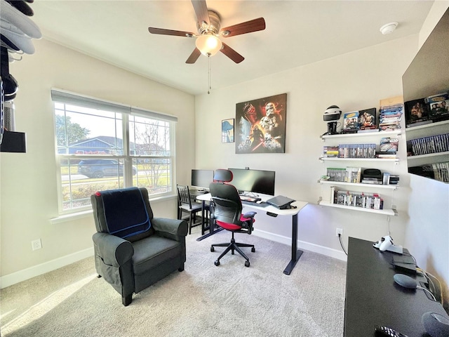 carpeted office space with a ceiling fan and baseboards