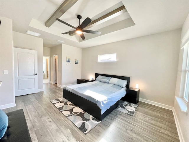 bedroom with light wood-style floors, baseboards, a raised ceiling, and a ceiling fan