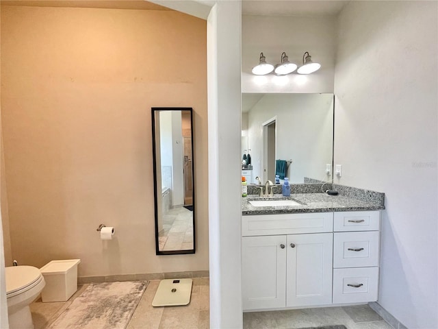 bathroom with baseboards, vanity, and toilet