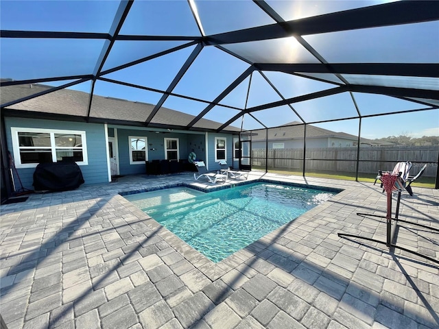 view of pool with a patio, fence, glass enclosure, and a grill