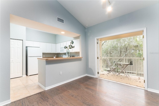 kitchen featuring visible vents, light wood-style flooring, white cabinetry, white appliances, and a peninsula