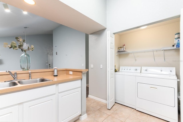 laundry area featuring light tile patterned floors, a sink, washer and dryer, laundry area, and baseboards