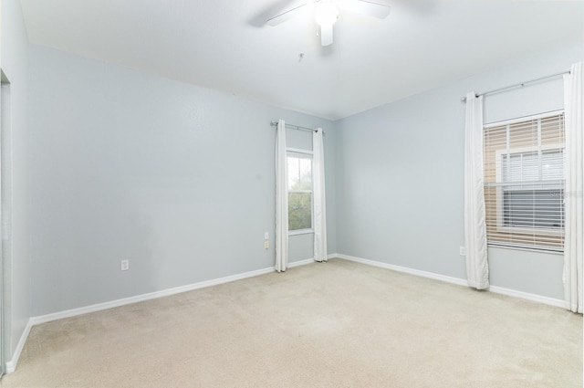 empty room featuring baseboards, ceiling fan, and light colored carpet