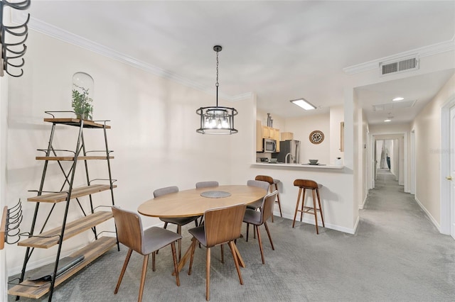 carpeted dining room with visible vents, crown molding, and baseboards